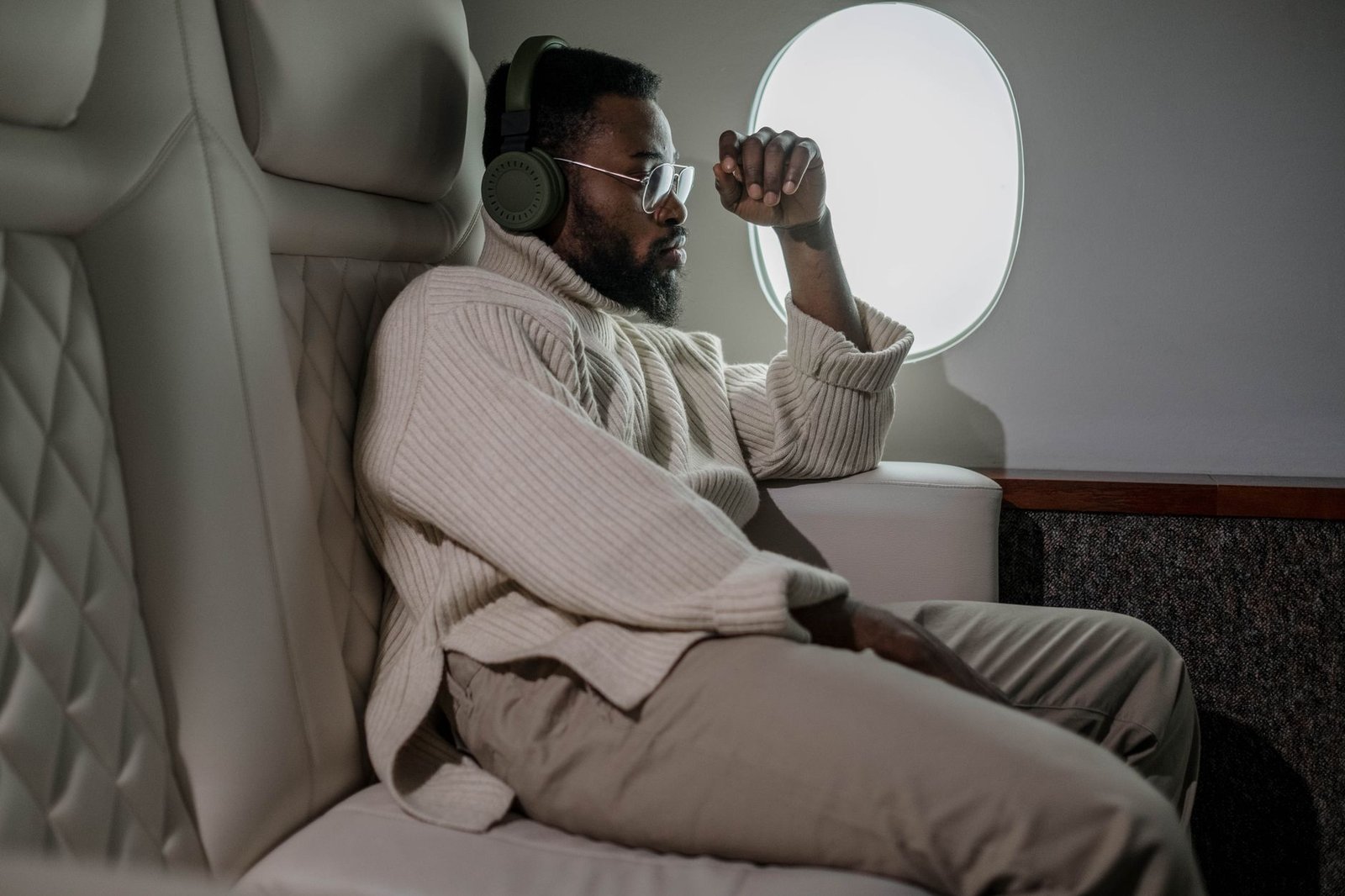 Man wearing over-ear noise cancelling headphones relaxing on a plane
