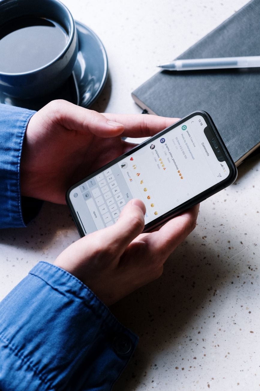 Person checking the messages app on an Android phone at a desk with coffee