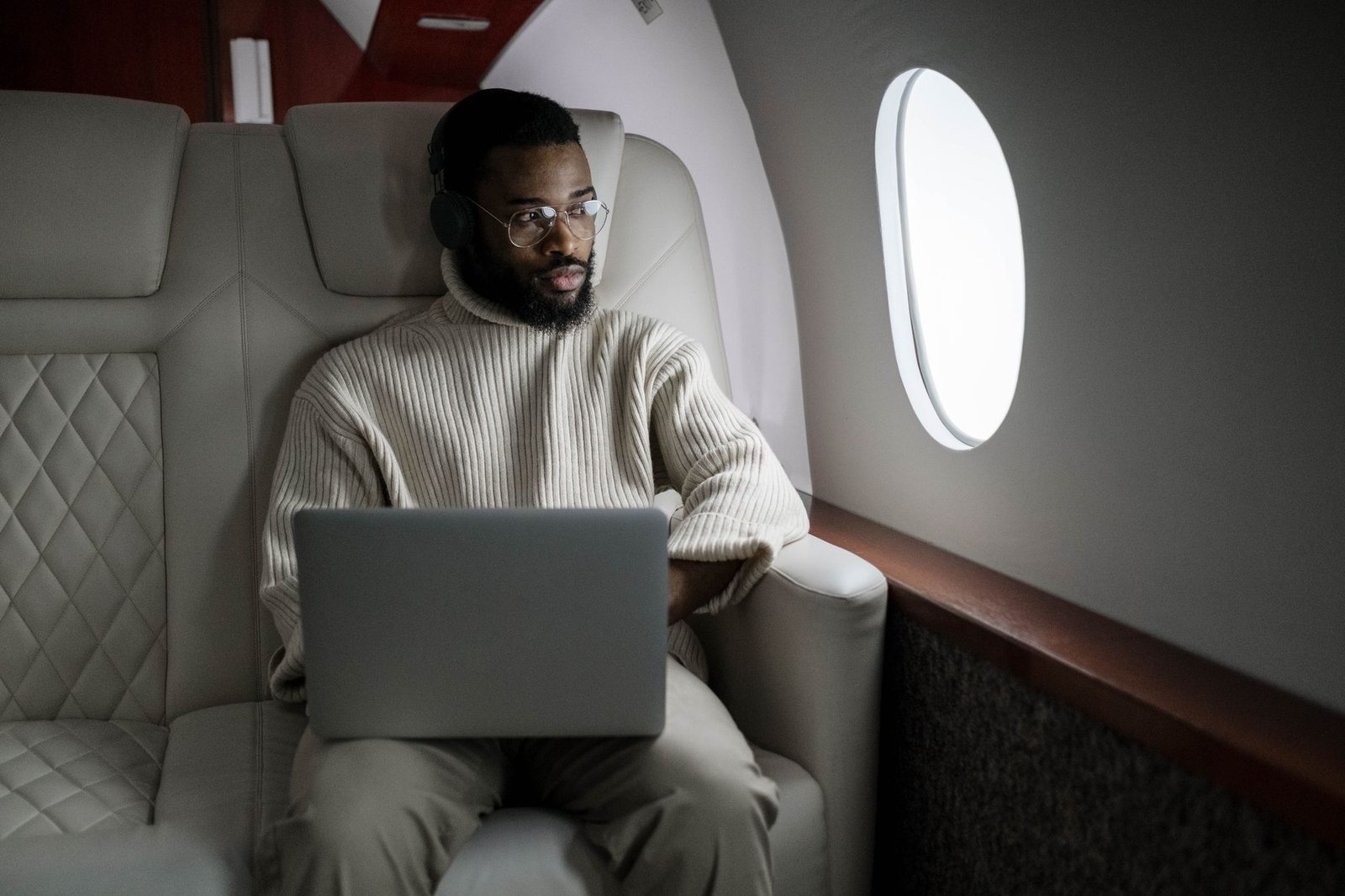 A traveler using a laptop and headphones on a plane, the frequent-flyer case for AR glasses