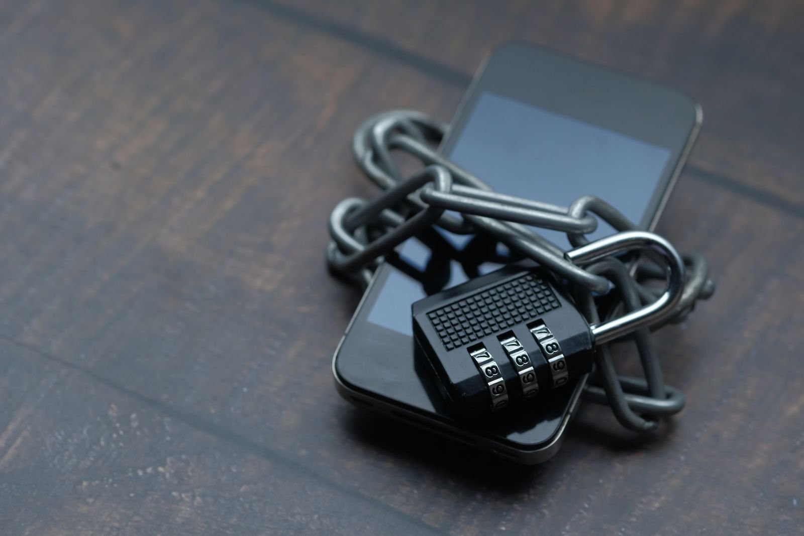 A smartphone wrapped in a chain and padlock, symbolizing bank account privacy and security.