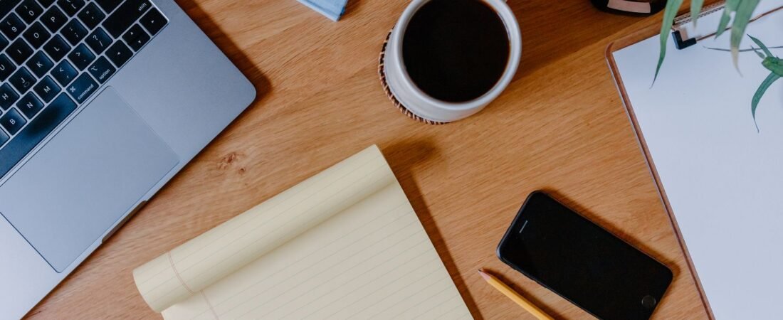 Phone on a desk with a notepad and coffee, ready to cancel unused subscriptions in a 15-minute audit.