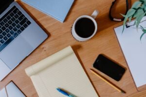 Phone on a desk with a notepad and coffee, ready to cancel unused subscriptions in a 15-minute audit.
