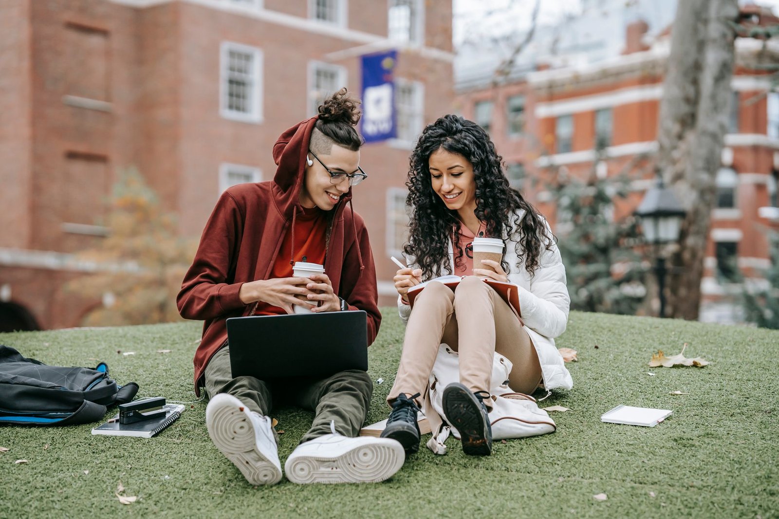 College student on campus using tech from the everyday-carry kit: laptop, earbuds, and coffee