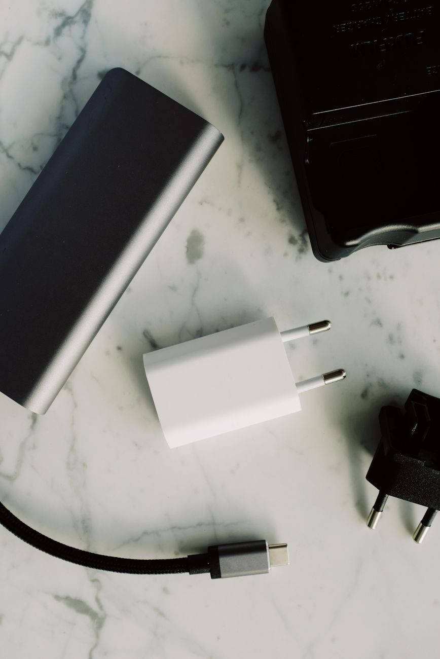 Flat lay of college tech essentials for girls: power bank, earbuds, tracker, and cable kit