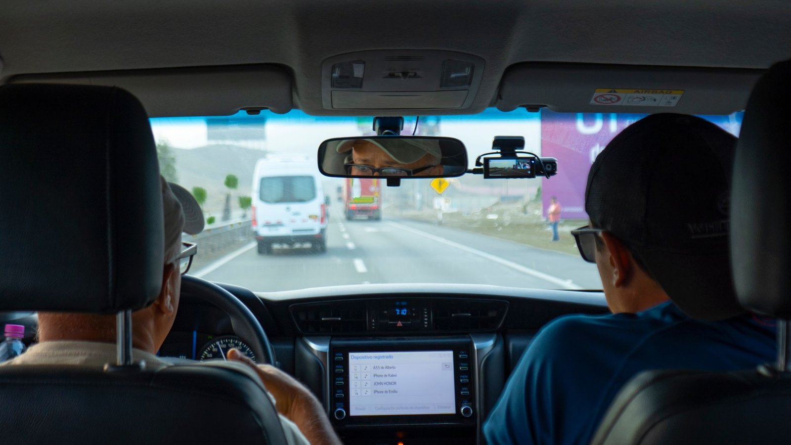 Front and rear dash cam setup installed in a car on the road