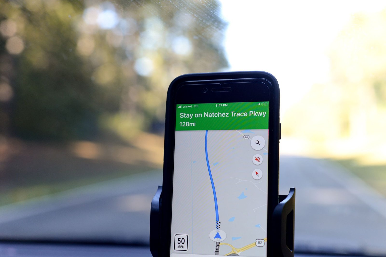 Smartphone showing a mapped road trip route with speed data on a windshield mount