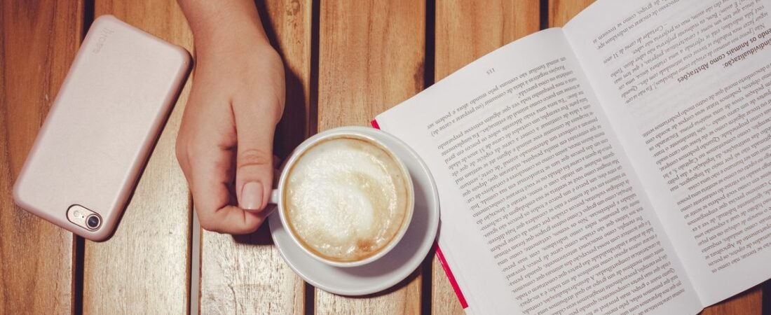 A phone set aside next to coffee and a book, the calm the best screen time app 2026 helps you reclaim