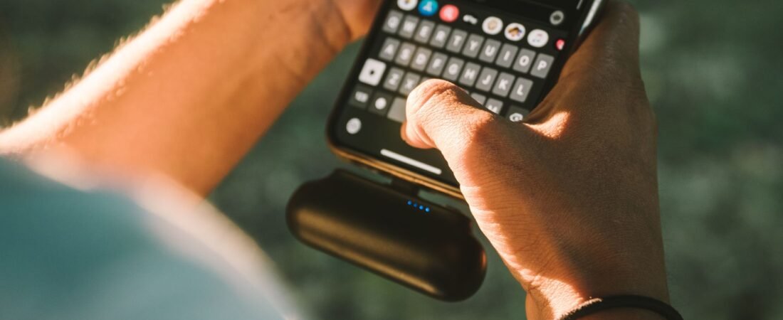 How to choose a power bank: a person charging a phone with a portable power bank on the go