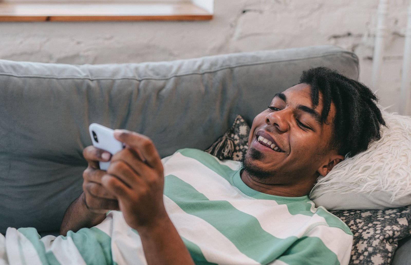 A relaxed person casually using a chat app on their phone at home
