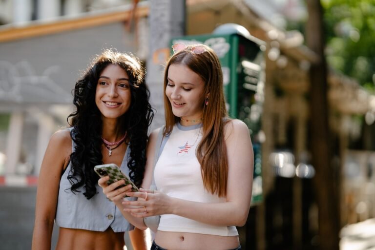 Two young women looking at a phone in bright summer sun, a common phone overheating in summer situation