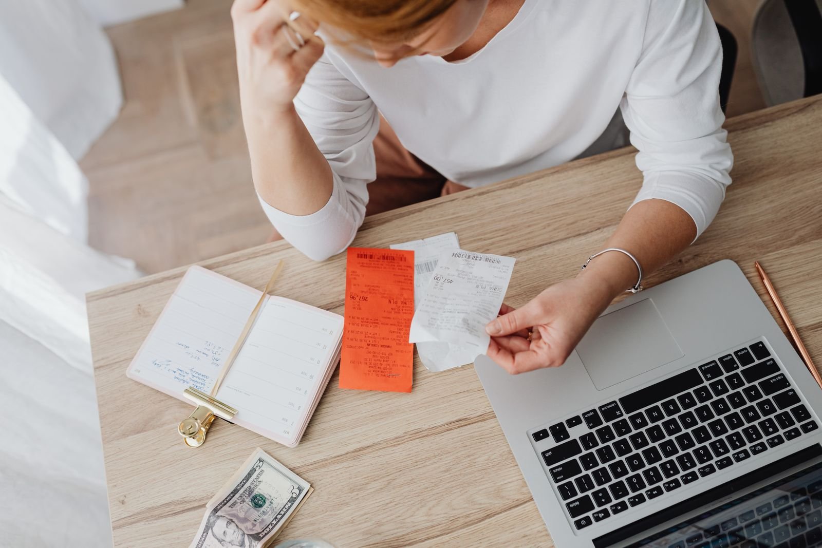 Person at a table reviewing receipts and a laptop to decide which subscriptions to keep or cancel.