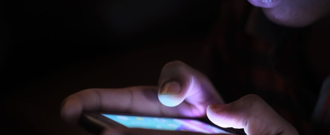 AI voice cloning scam concept: a phone lighting up at night with an unknown caller