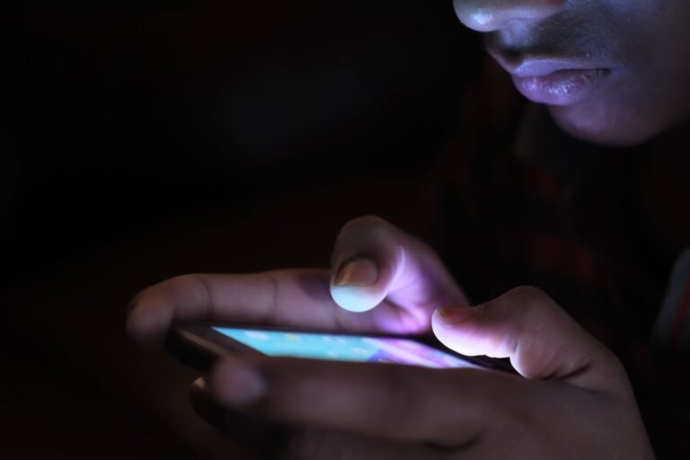 AI voice cloning scam concept: a phone lighting up at night with an unknown caller