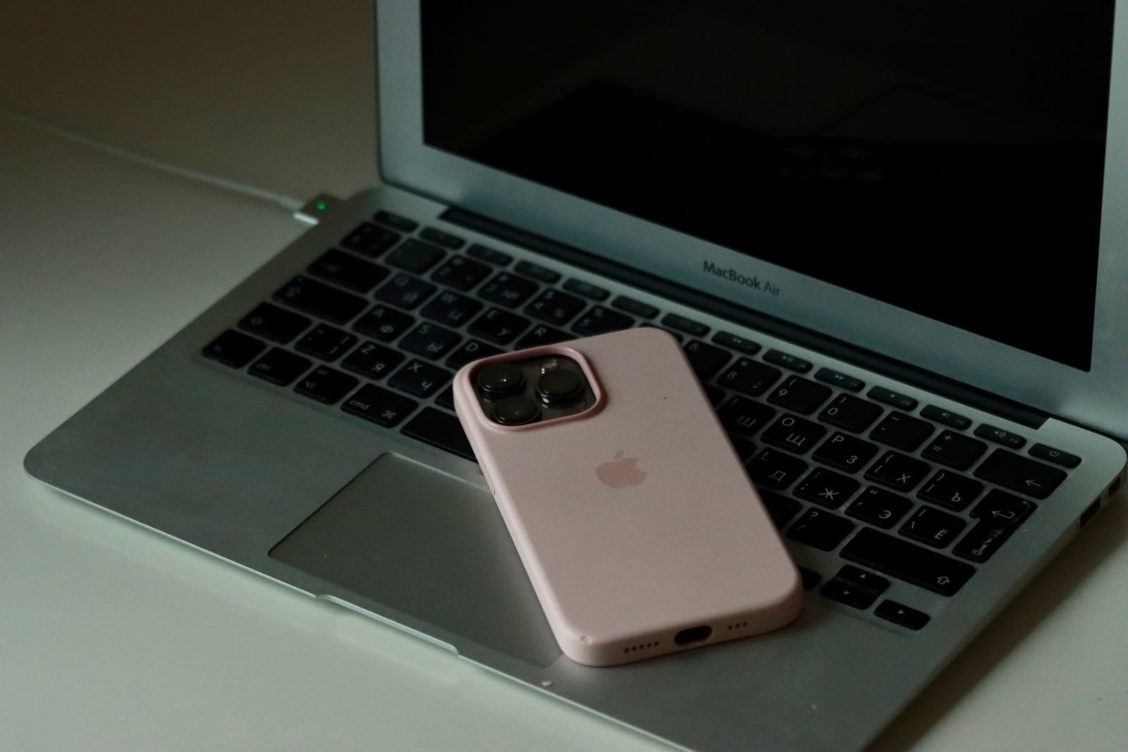A compact USB-C charger topping up a phone resting on a laptop