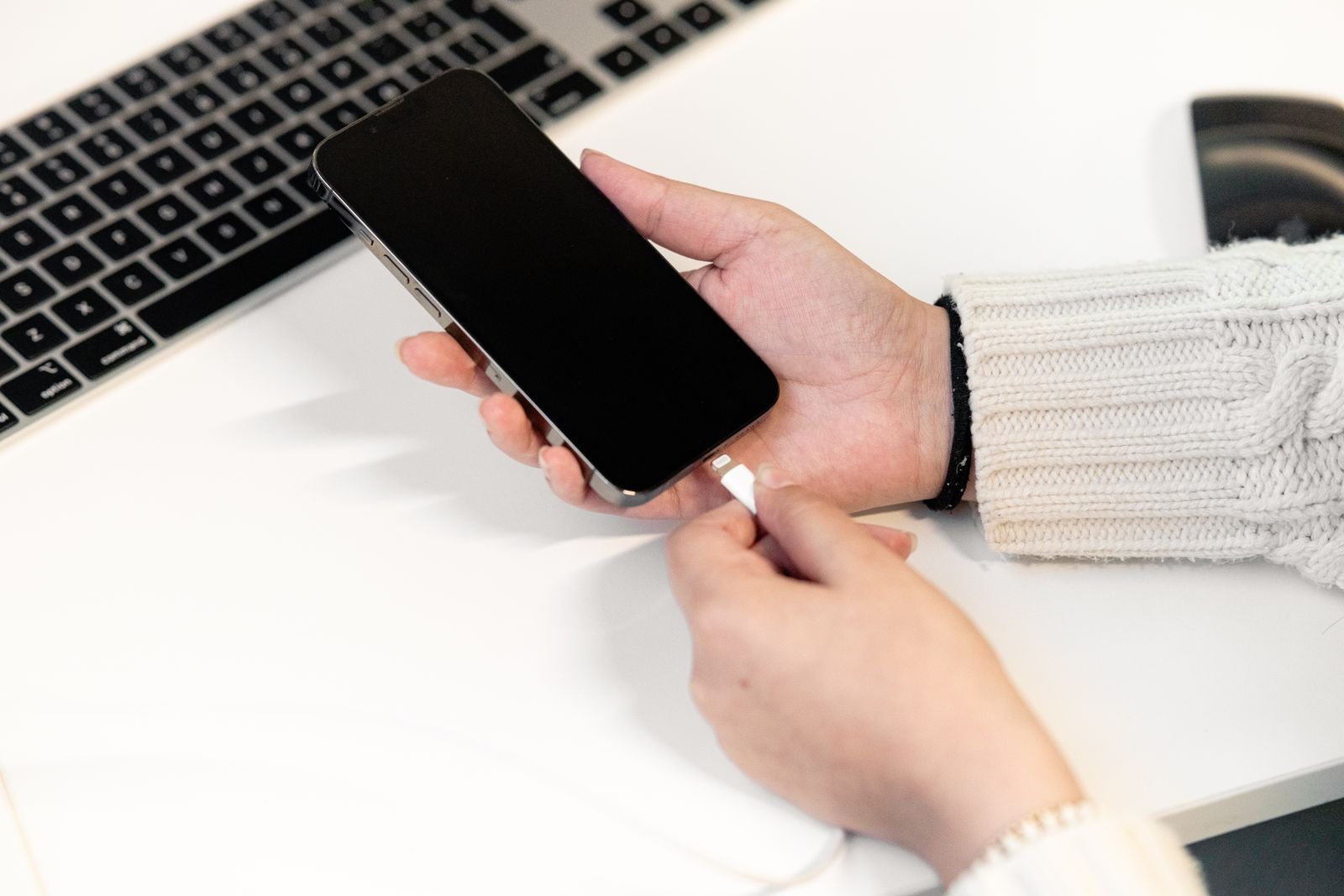 A phone charging from a USB-C charger next to a laptop on a desk
