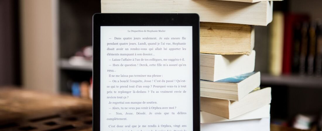 Kindle vs Kobo 2026: an e-reader beside a stack of books