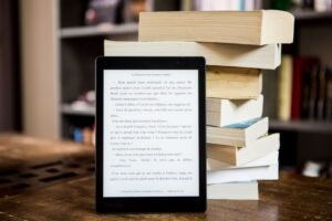 Kindle vs Kobo 2026: an e-reader beside a stack of books