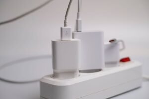 White power strip with chargers plugged in, the standby devices a smart plug can switch off to cut vampire power.