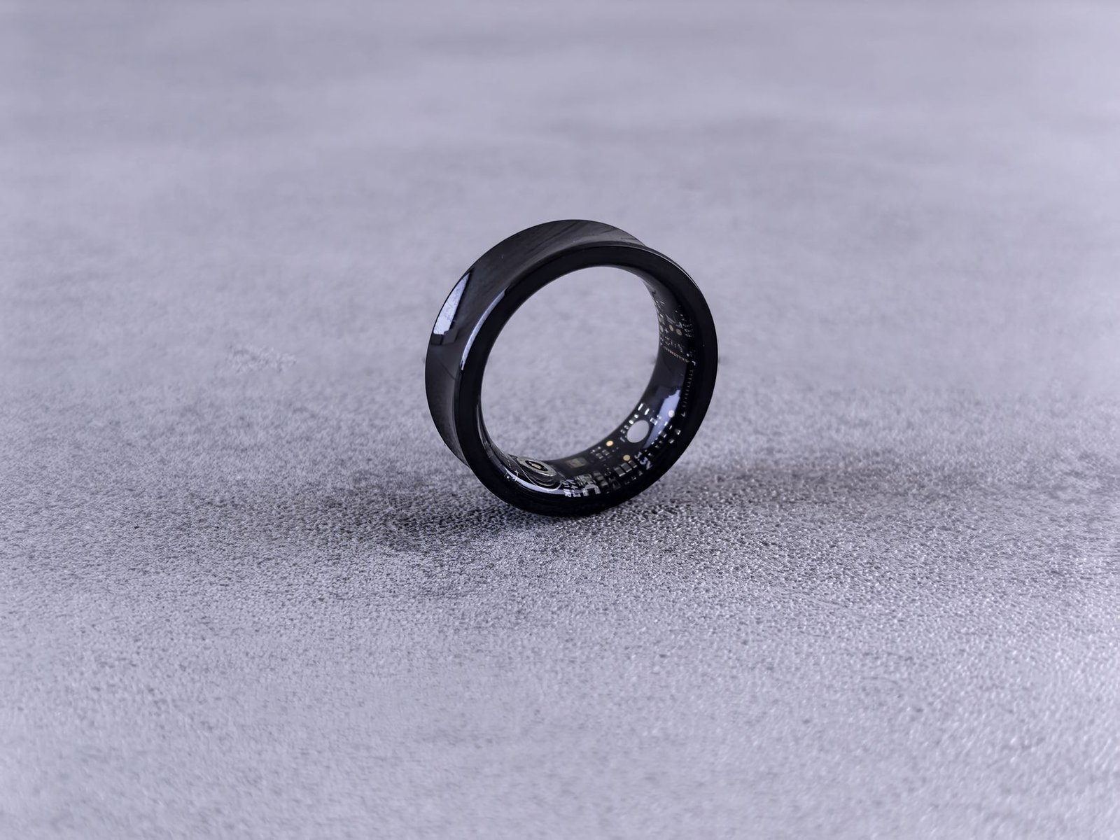 Close-up of a black smart ring showing its internal health sensors