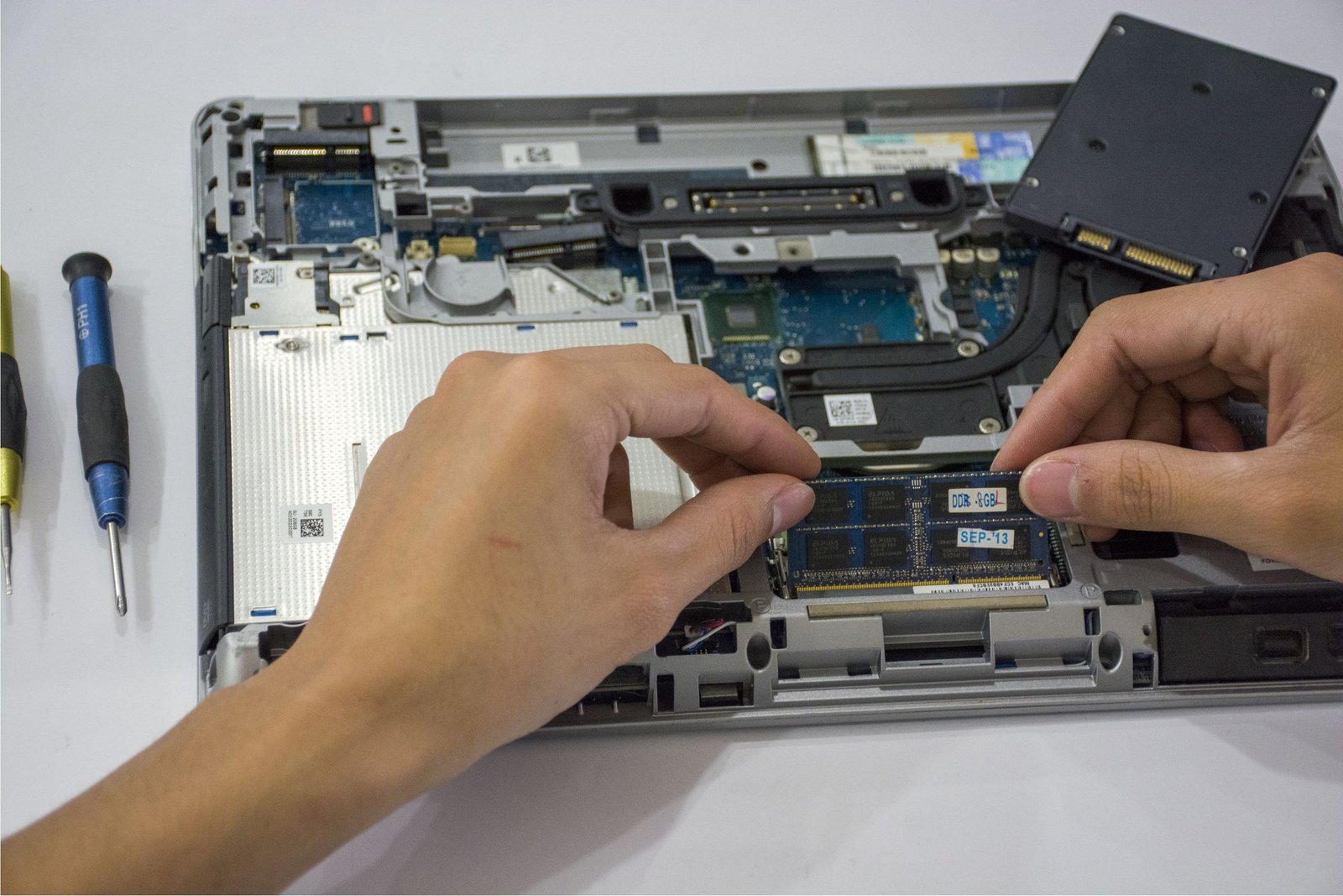 Close-up of hands installing a SO-DIMM memory stick into a laptop, showing whether a laptop has soldered or upgradeable RAM