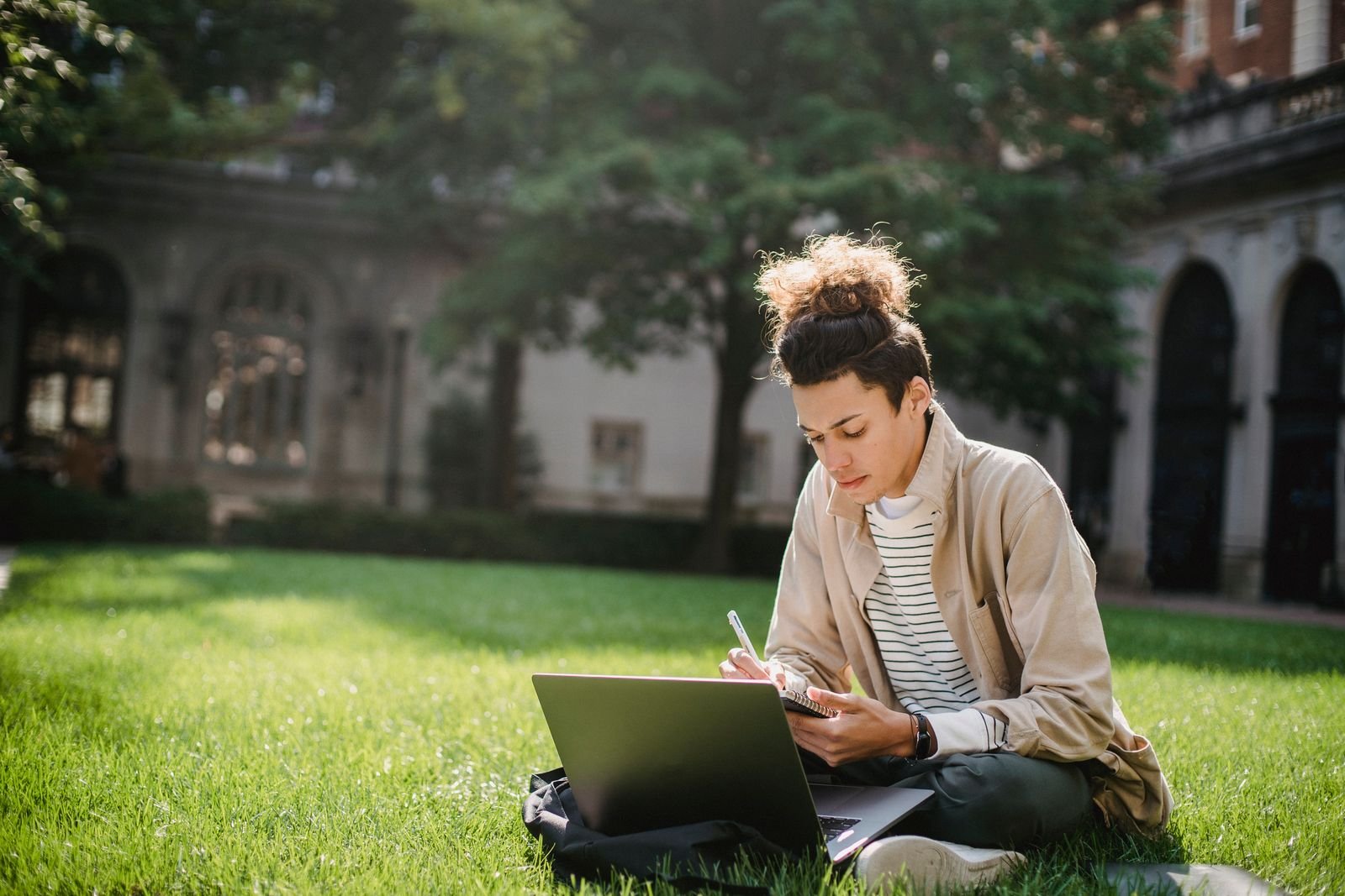 A student studying on a laptop on a campus lawn while choosing a laptop