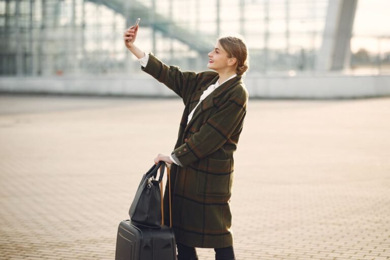 Cheerful traveler using her phone with a suitcase, connected abroad after landing