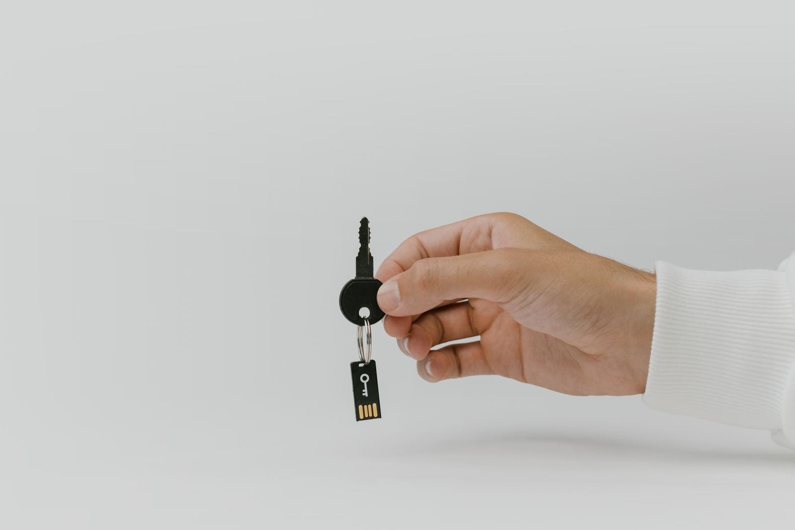 A USB security key held on a keyring as a passkey backup for a critical account