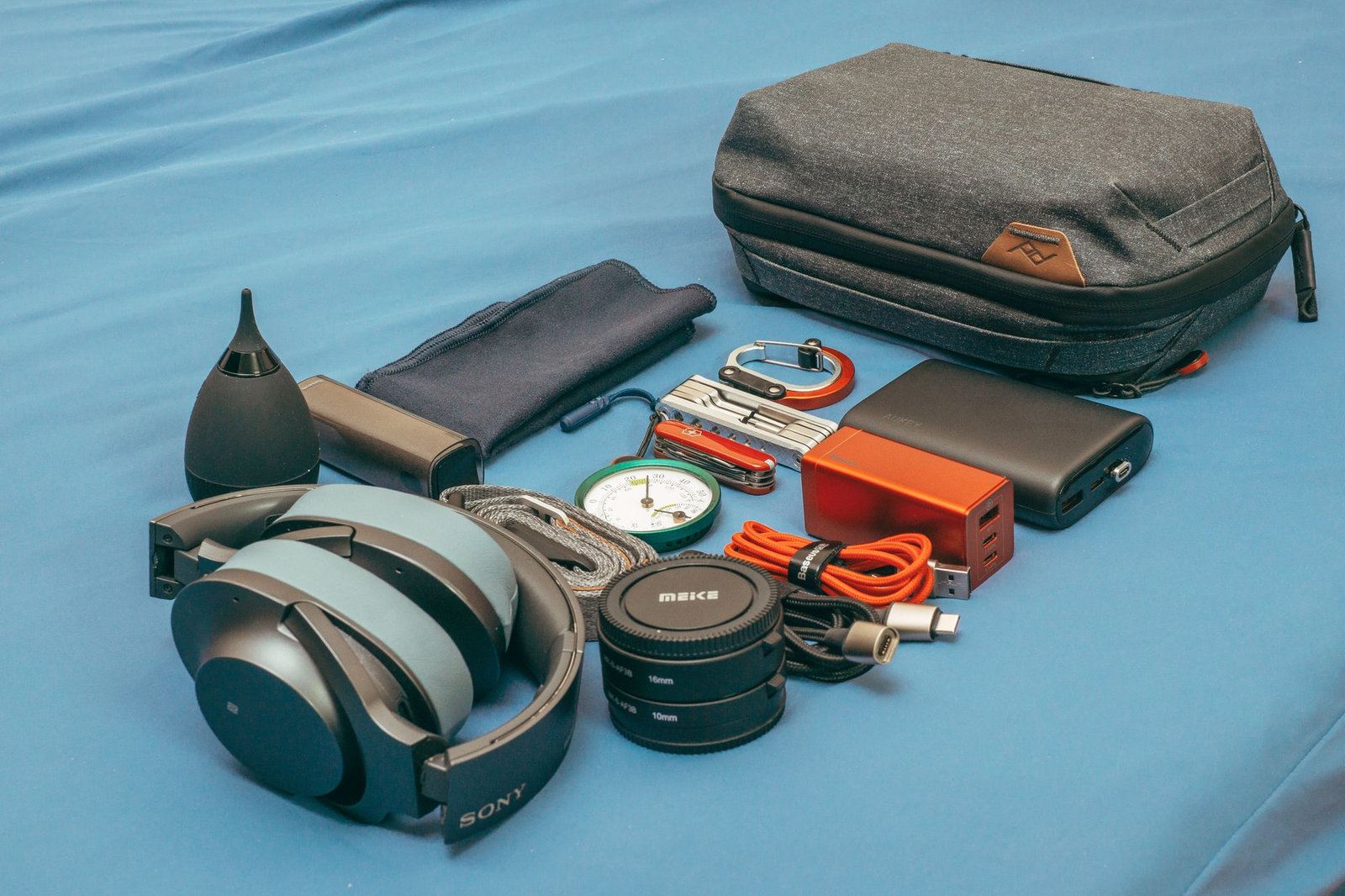 A compact travel tech kit with a charger, coiled USB-C cable, power bank, and headphones.
