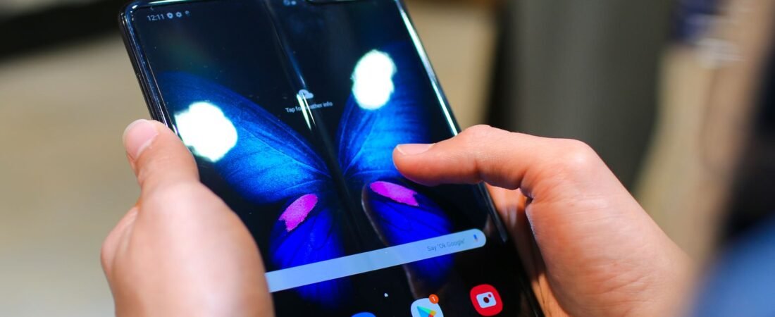 Someone holding an open book-style foldable phone with a vivid display