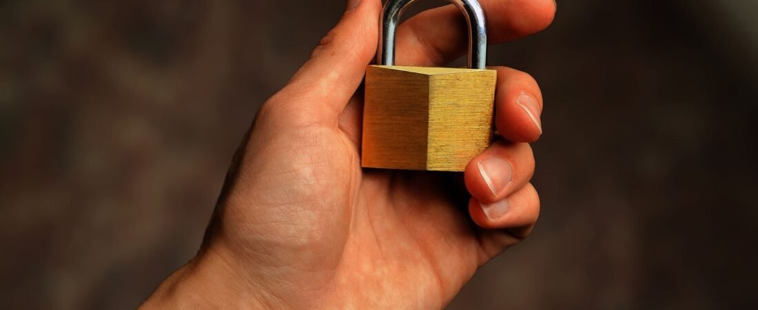 A brass padlock held in a hand, representing password protection and login security