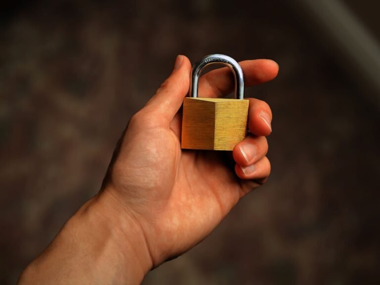 A brass padlock held in a hand, representing password protection and login security