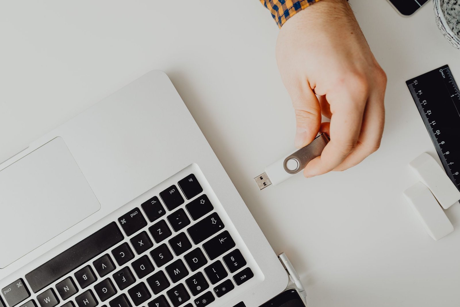 A hand moving data onto a laptop, like migrating saved passwords into a dedicated vault