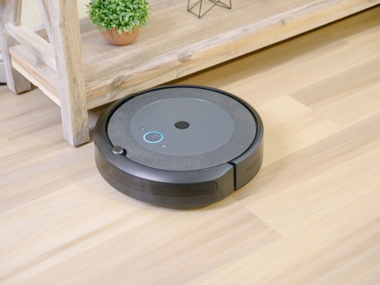 Robot vacuum with a LiDAR turret cleaning a bright hardwood living room, illustrating the robot vacuum features worth it in 2026.