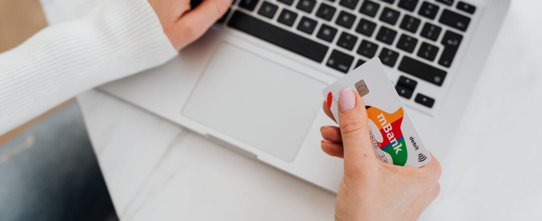 Shopper holding a credit card at a laptop checkout screen during a holiday sale